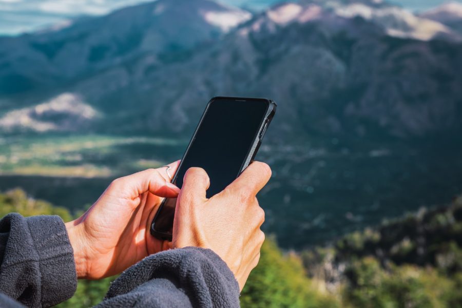 woman-s-hands-with-cell-phone-among-mountains